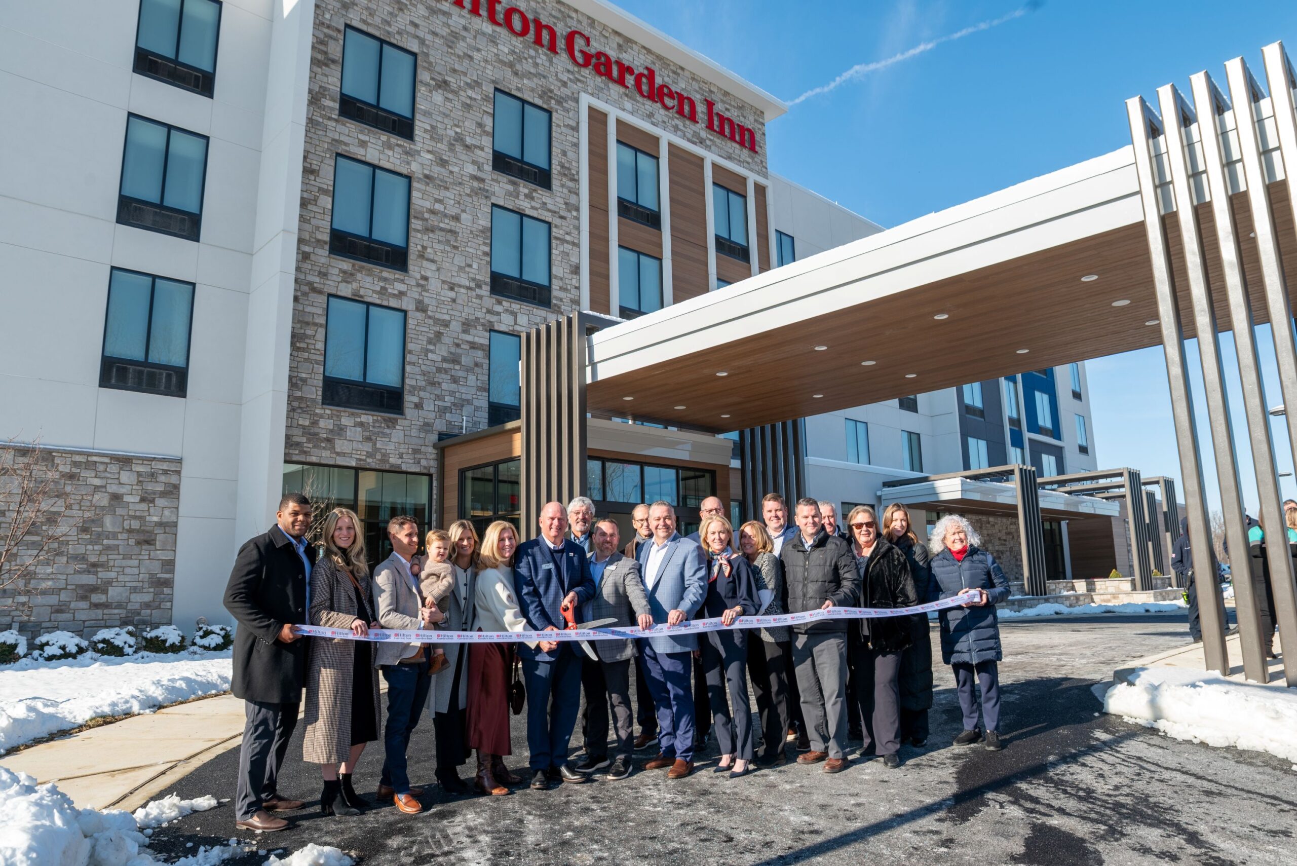 Group of people cutting a ribbon outside a Hilton Garden Inn hotel